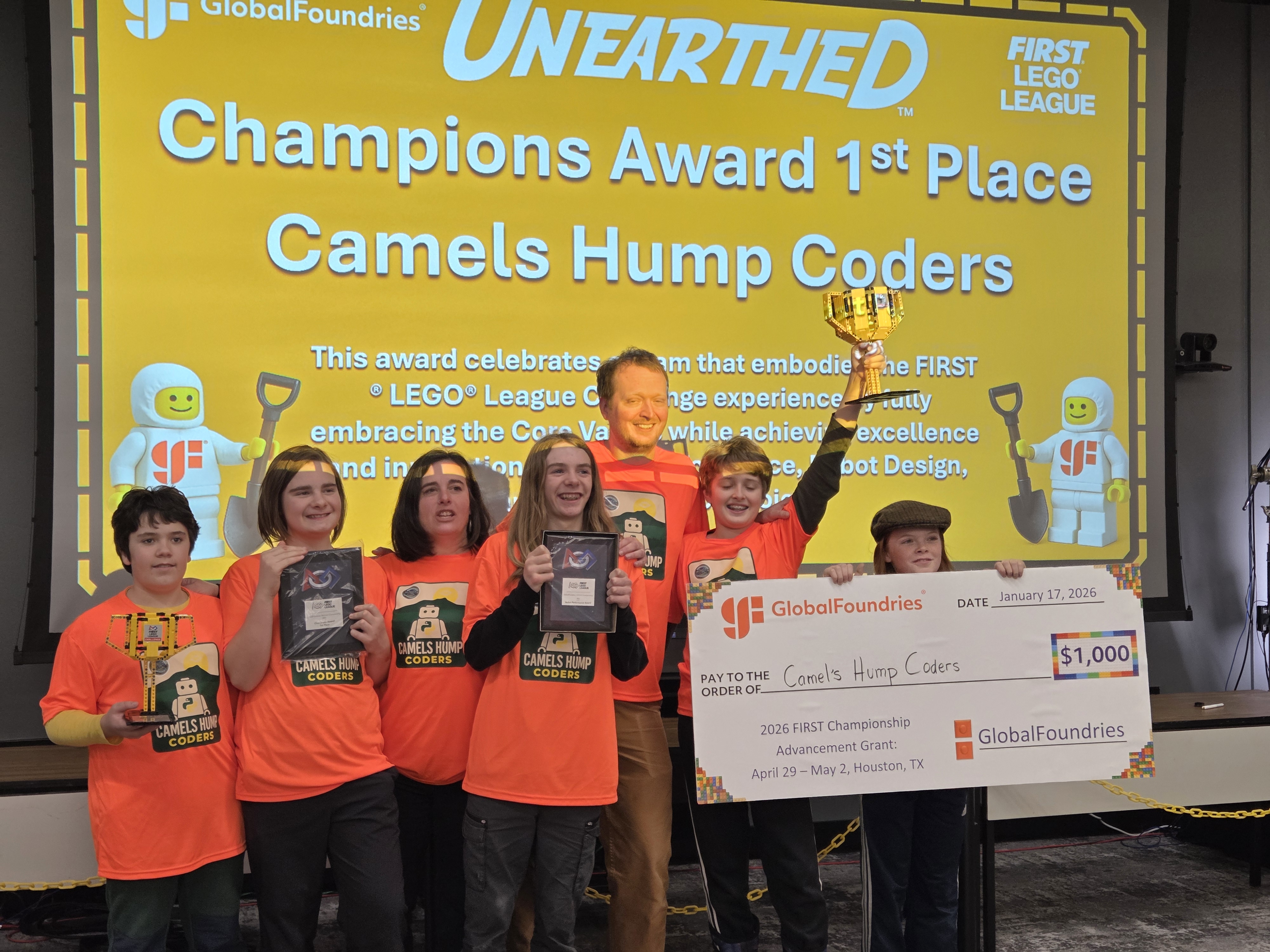 Team members celebrating with awards and a championship check