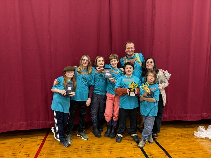 Camels Hump Coders posing with awards in front of a red curtain