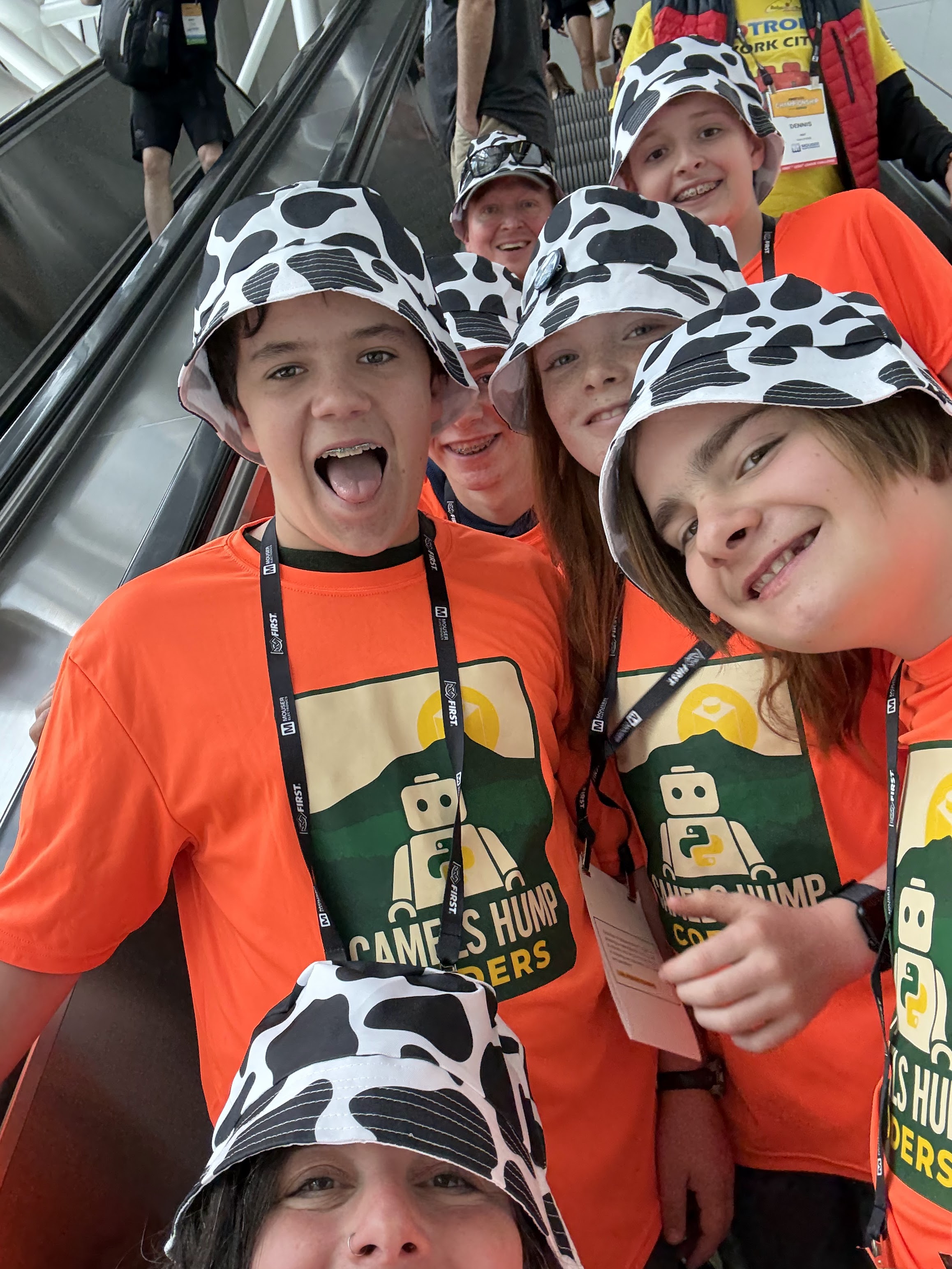 Team members smiling together in cow-pattern hats