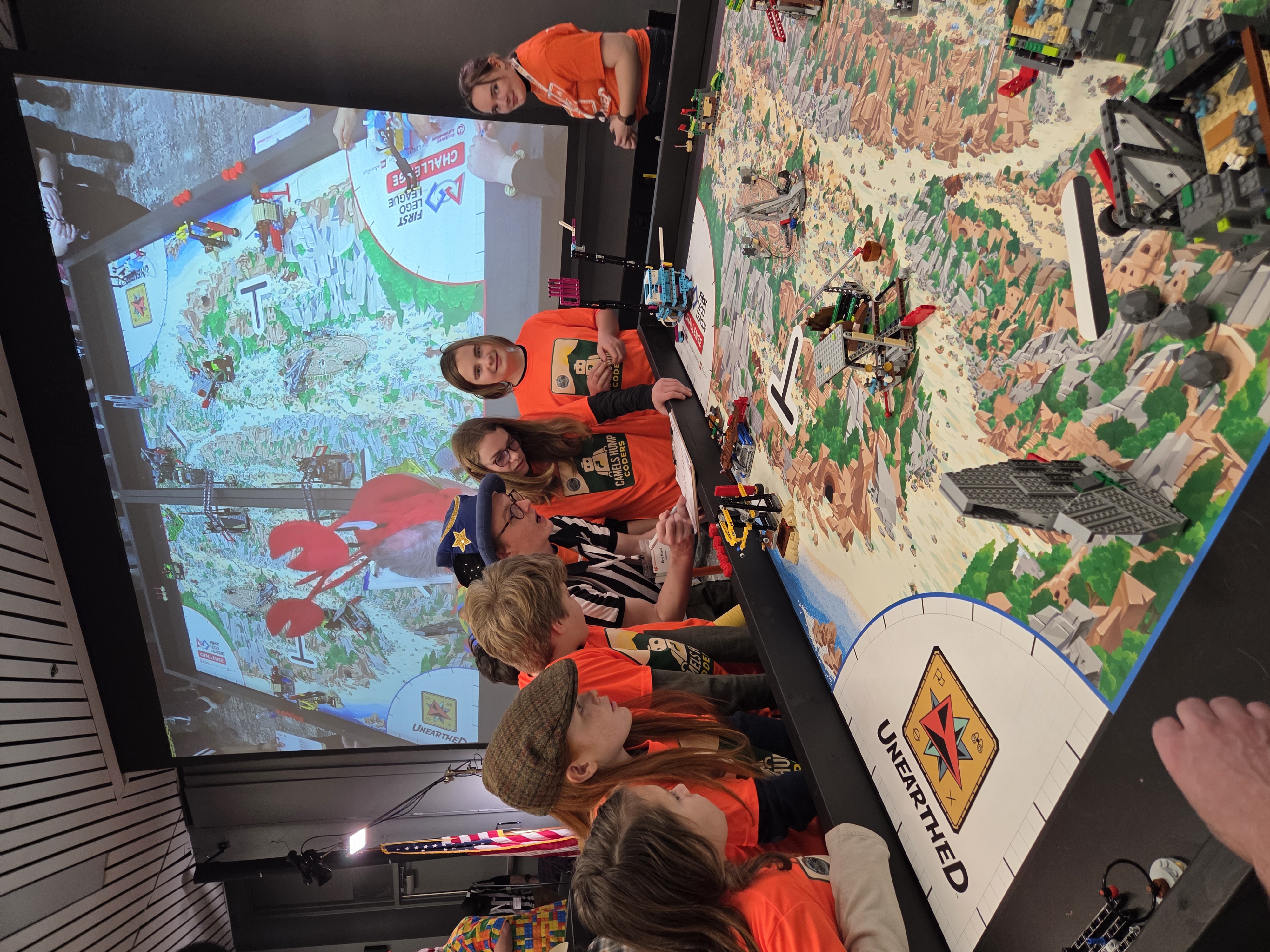 Team members and a referee reviewing the robot game table