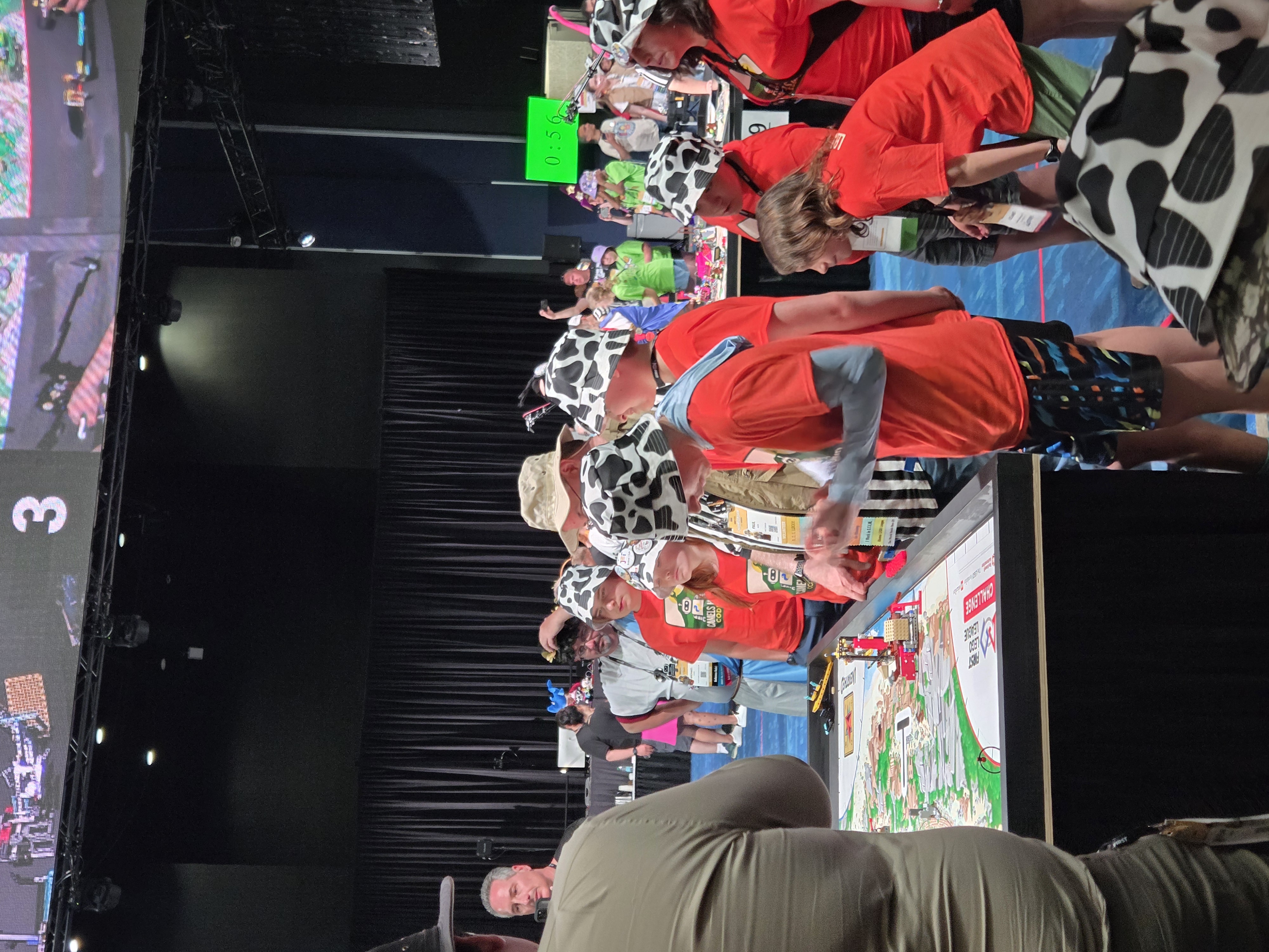Team members in cow-pattern hats at a World Festival robot table